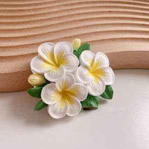 Flower-shaped hair clip with white and yellow flowers on a wooden background