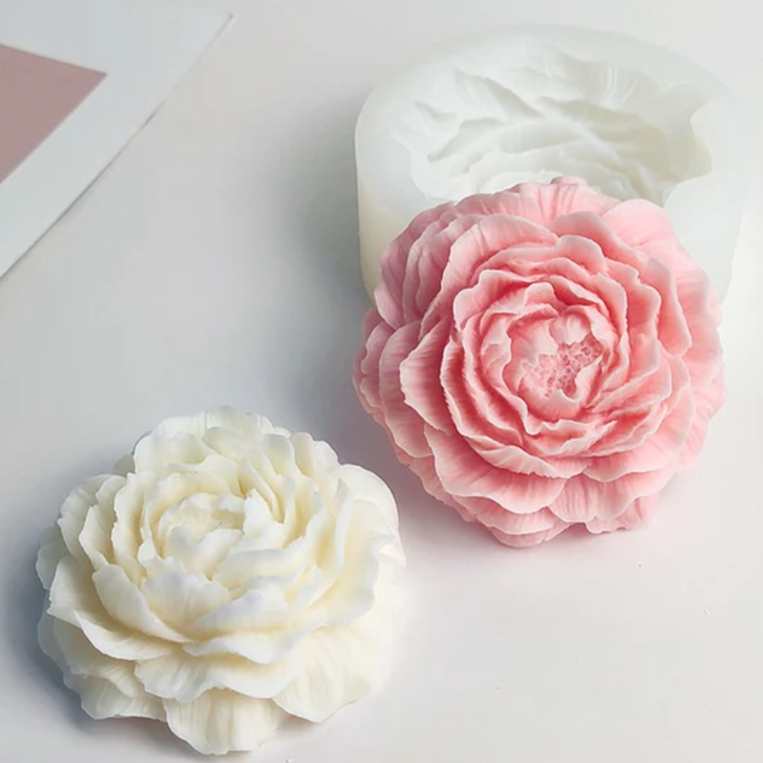 Two floral-shaped soaps, one white and one pink, on a light surface.